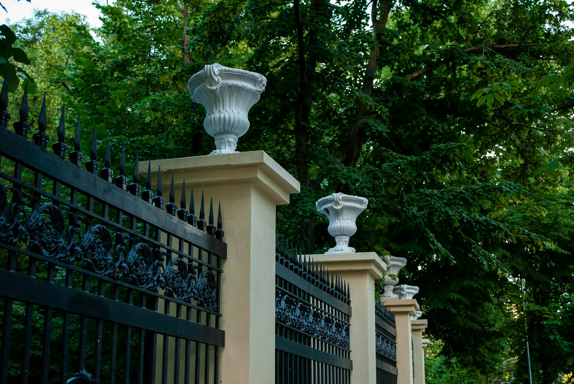 black metal gate near green trees during daytime